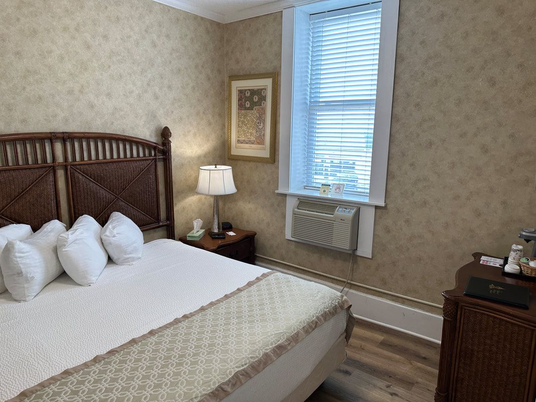 A bedroom with a bed , nightstand , lamp and window.