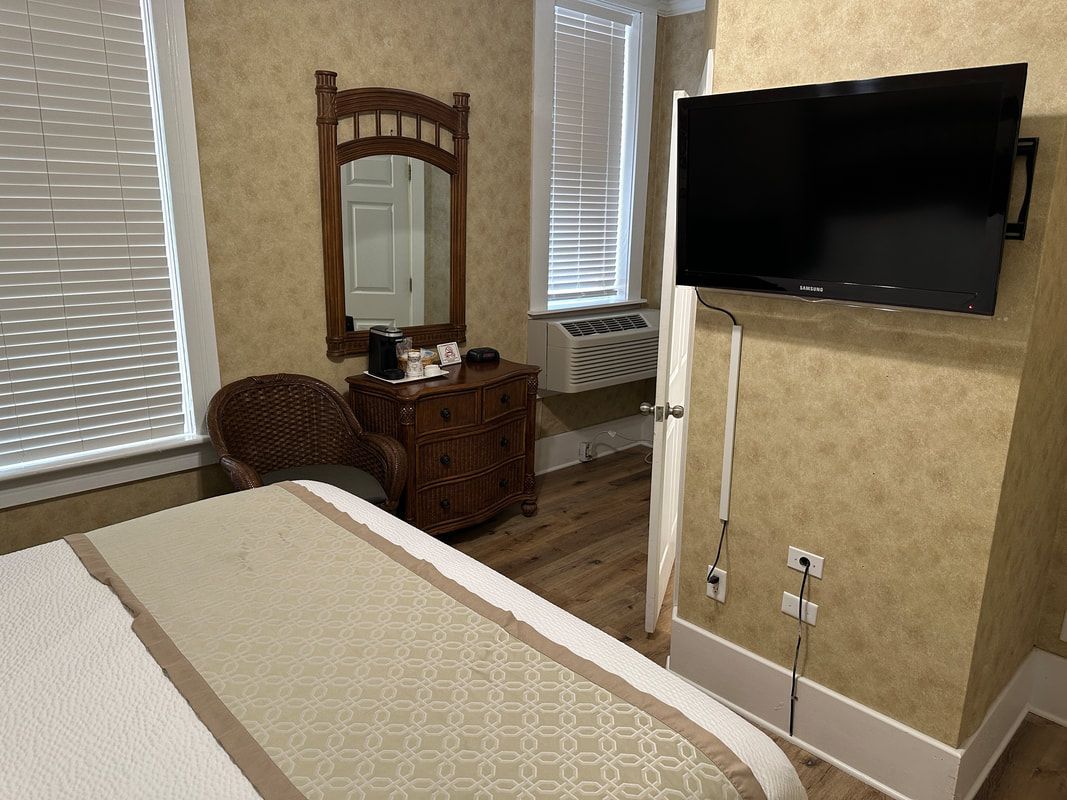 A hotel room with a bed , chair , dresser and television.