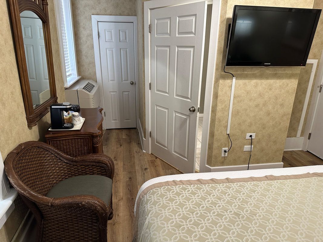 A hotel room with a bed , chair , television and mirror.
