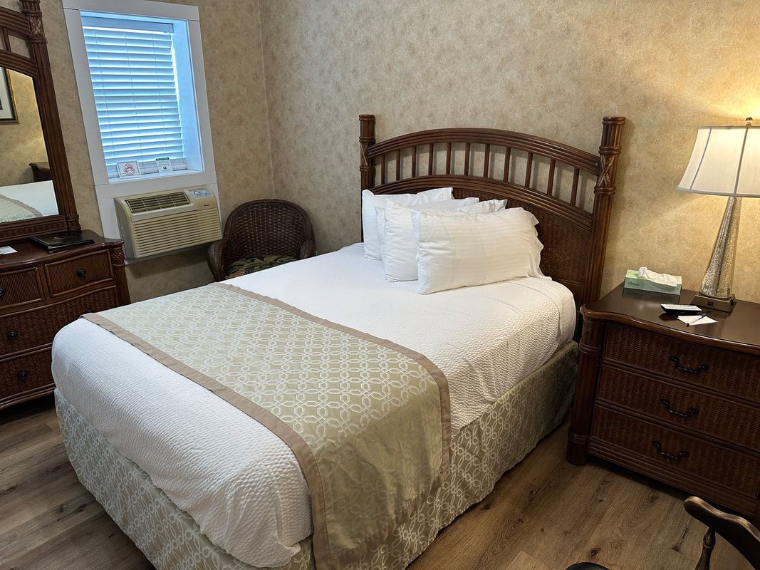 A hotel room with a bed , nightstand , dresser and mirror.