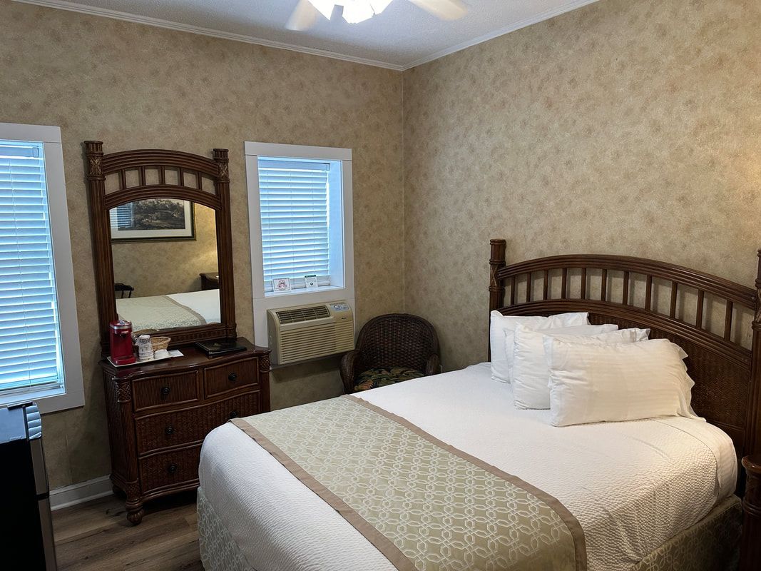 A bedroom with a bed , dresser , mirror and air conditioner.