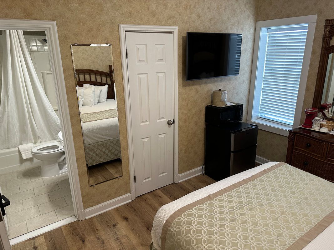 A hotel room with a bed , television , dresser and mirror.