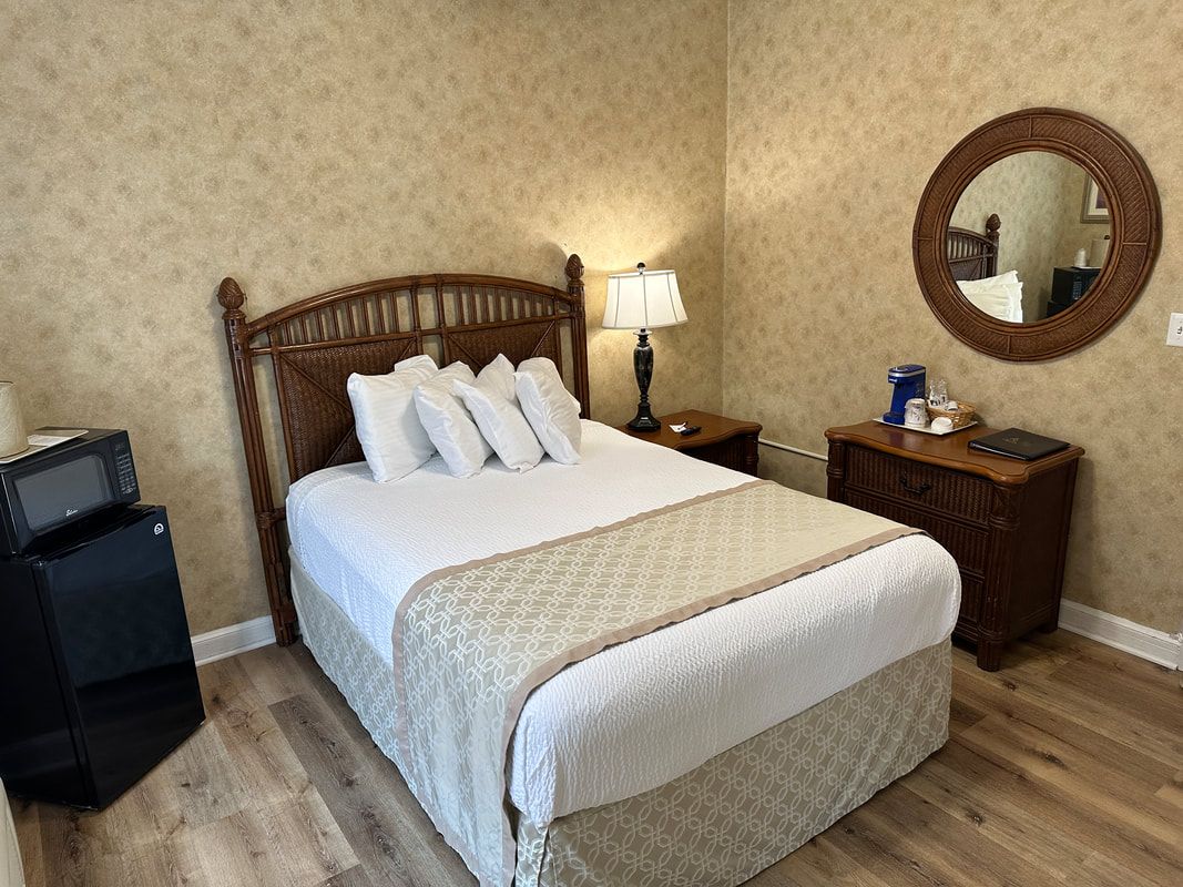 A hotel room with a bed , nightstand , microwave , and mirror.