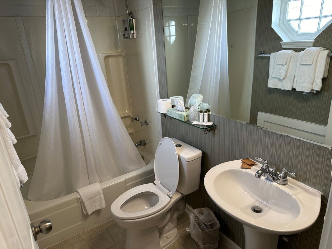 A bathroom with a toilet , sink , bathtub and mirror.