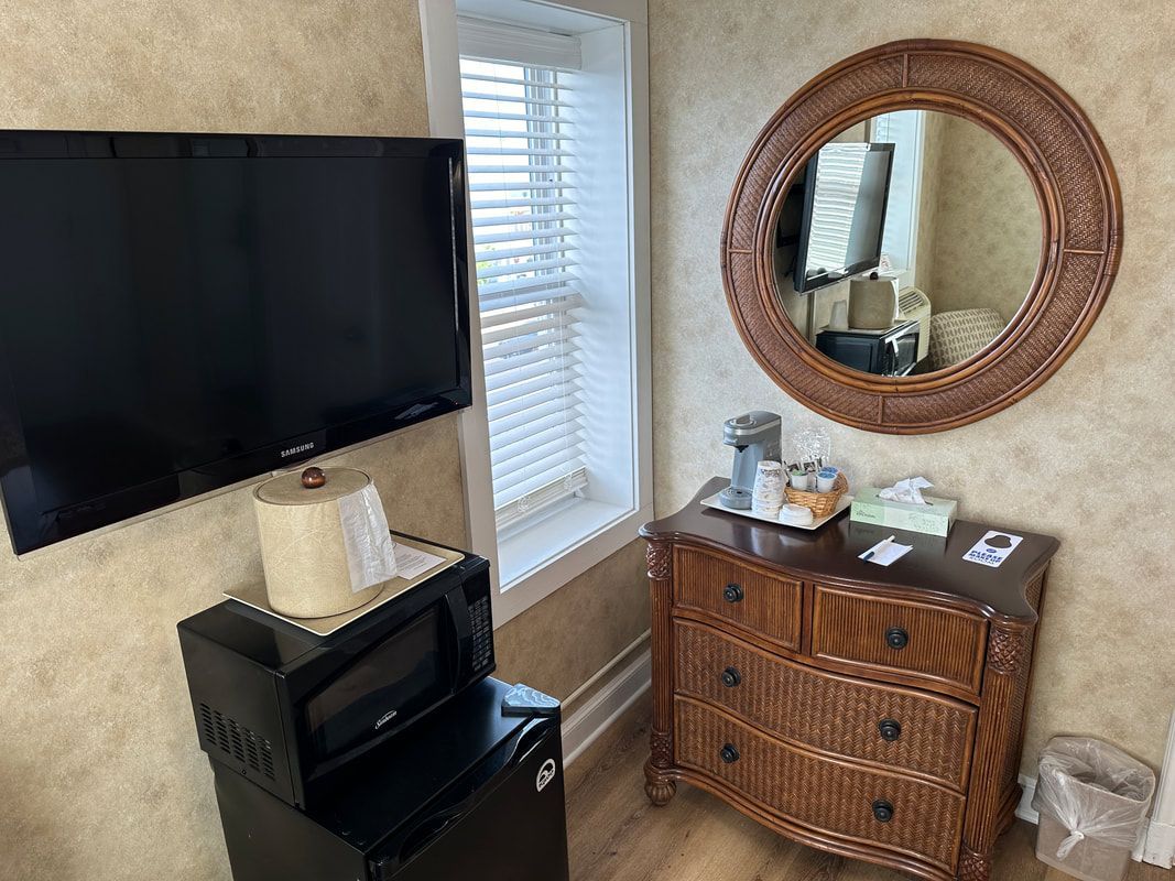 A hotel room with a dresser , microwave , television and mirror.