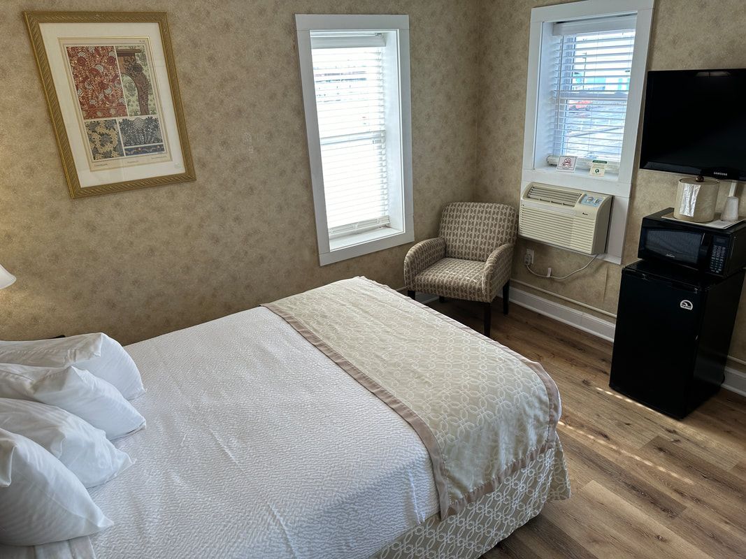 A hotel room with a bed , chair , television and microwave.