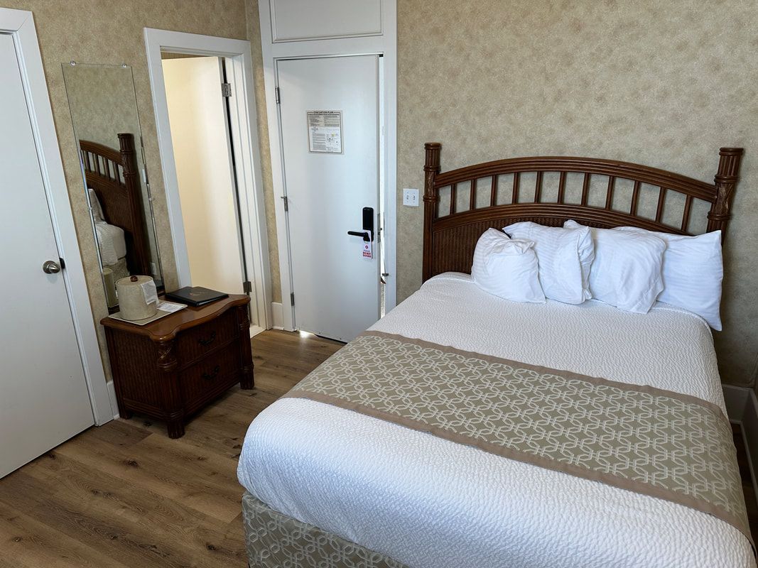 A hotel room with a bed , nightstand , mirror and door.