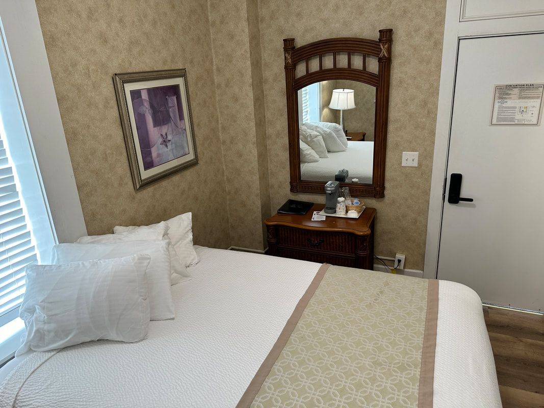 A hotel room with a bed , mirror and dresser.