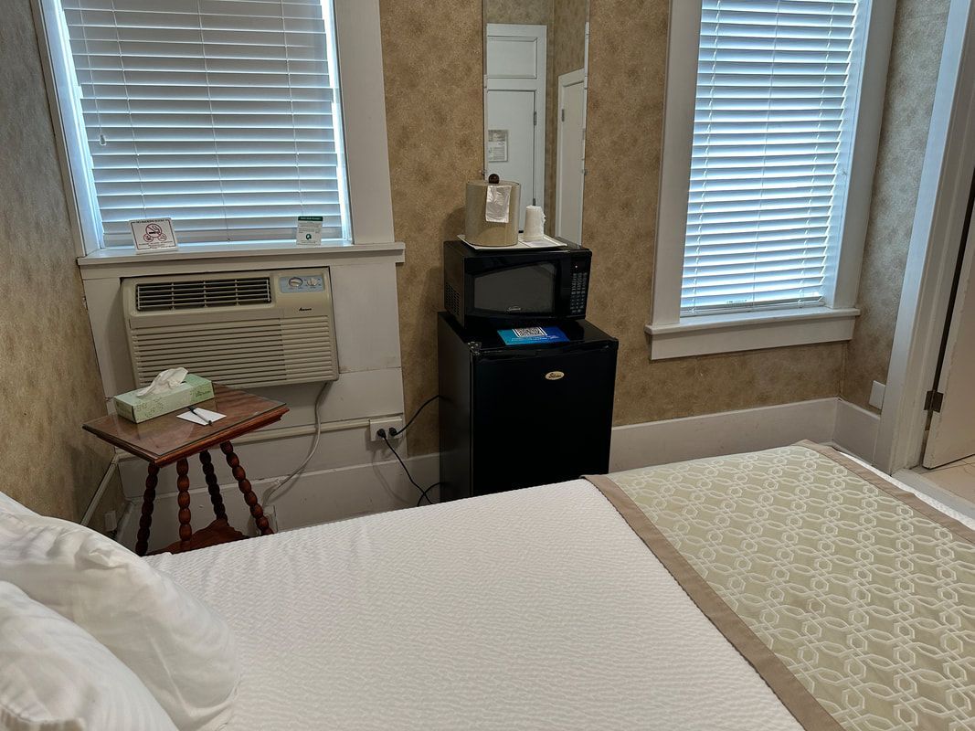 A bedroom with a bed , a refrigerator , a microwave and a mirror.