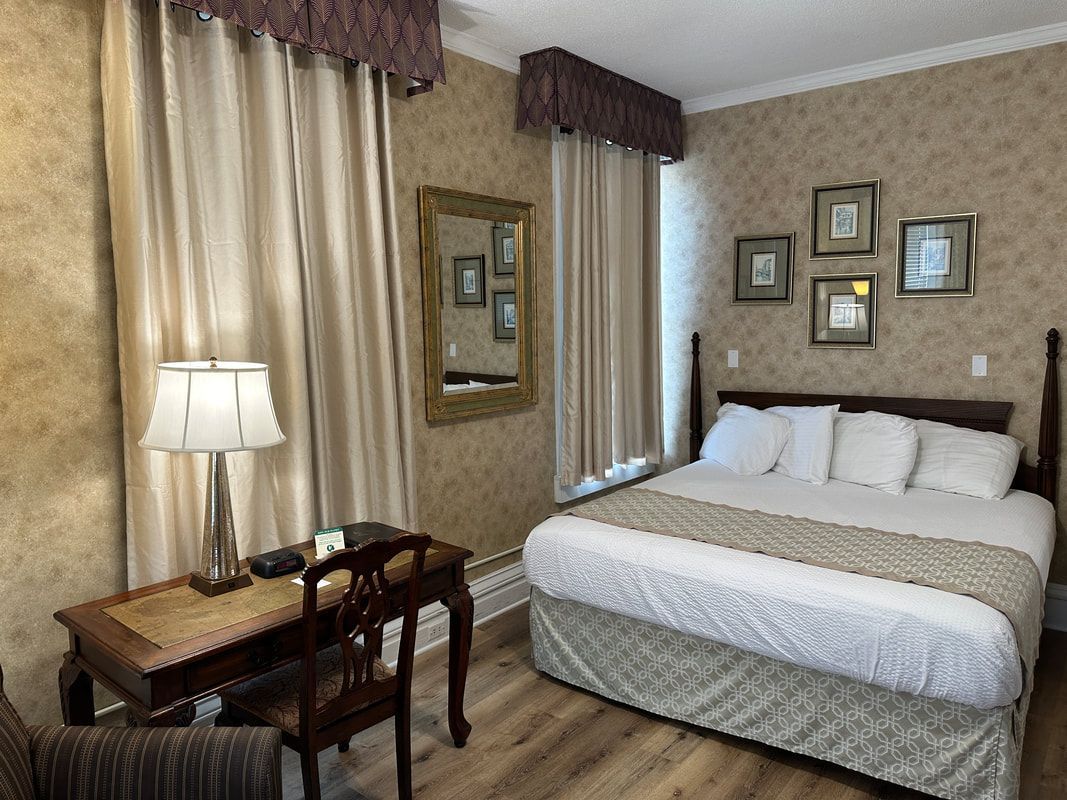 A hotel room with a bed , desk , chair and mirror.