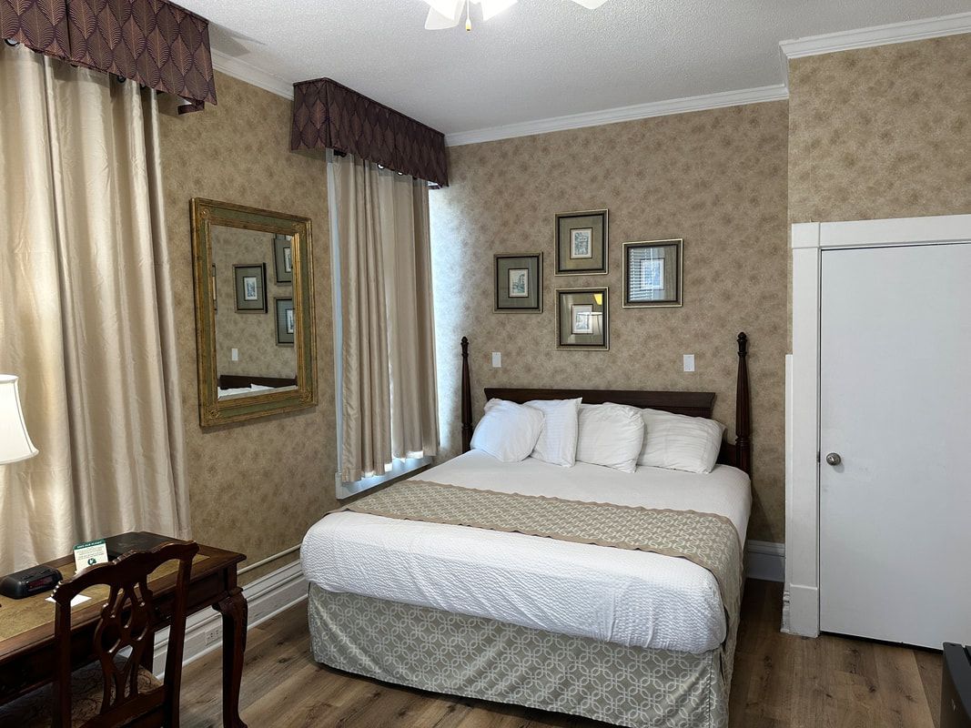 A hotel room with a king size bed , desk and mirror.