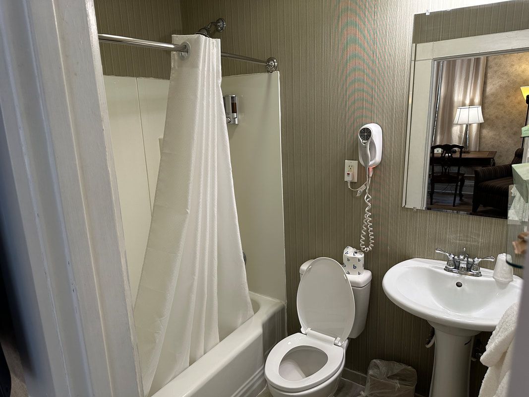 A bathroom with a toilet , sink , shower and mirror.