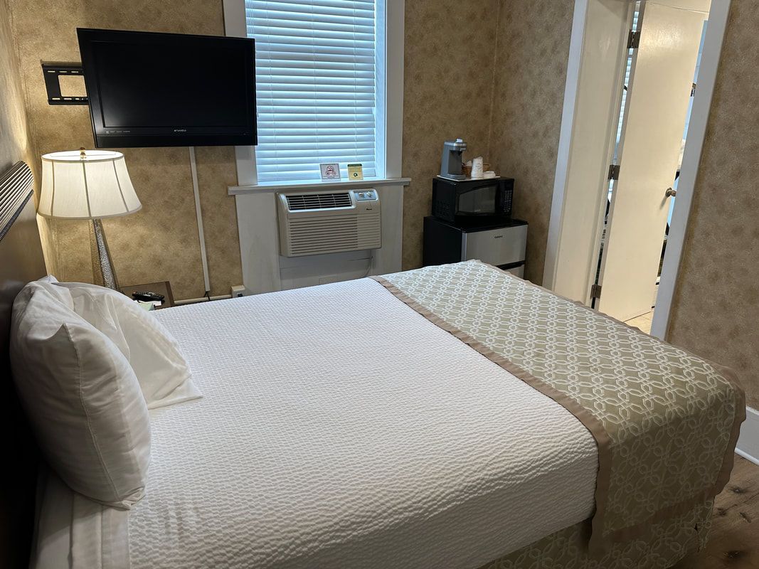 A hotel room with a bed , television and air conditioner.