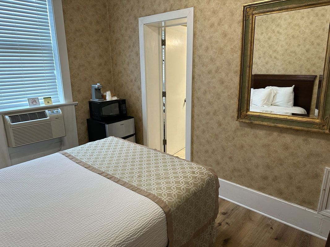 A bedroom with a bed , mirror and window.