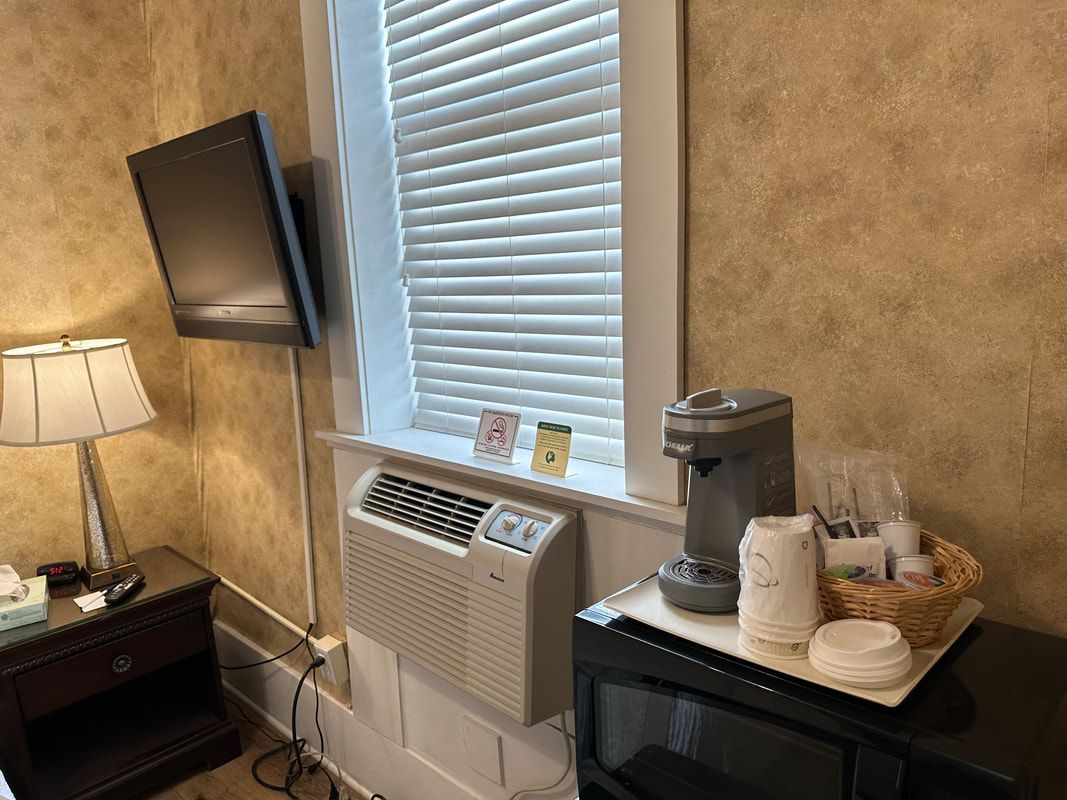 A hotel room with a microwave , coffee maker , and television.