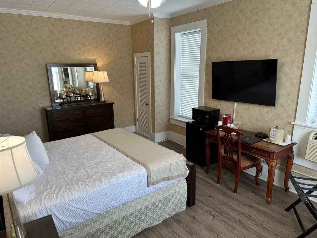 A hotel room with a bed , desk , chair and television.