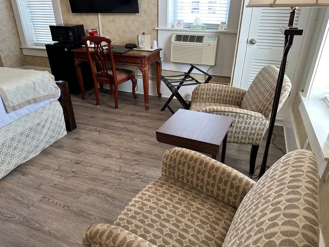 A hotel room with two beds , two chairs , a desk and a television.