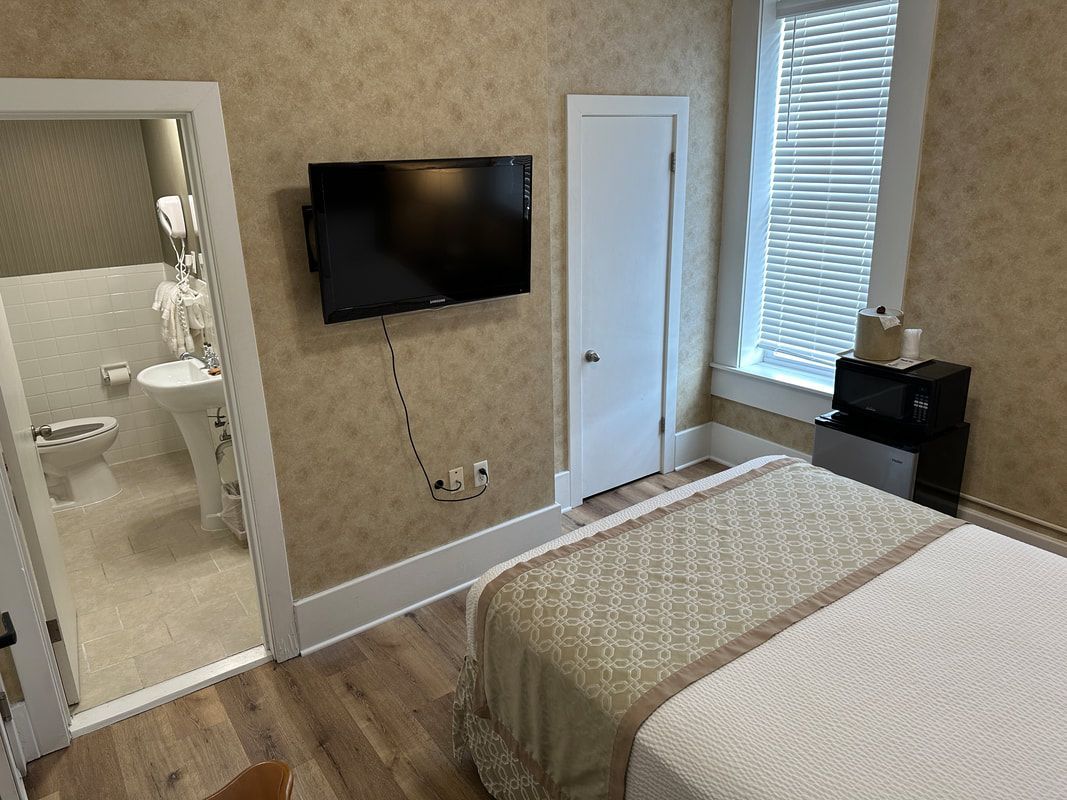 A hotel room with a bed , television , and bathroom.