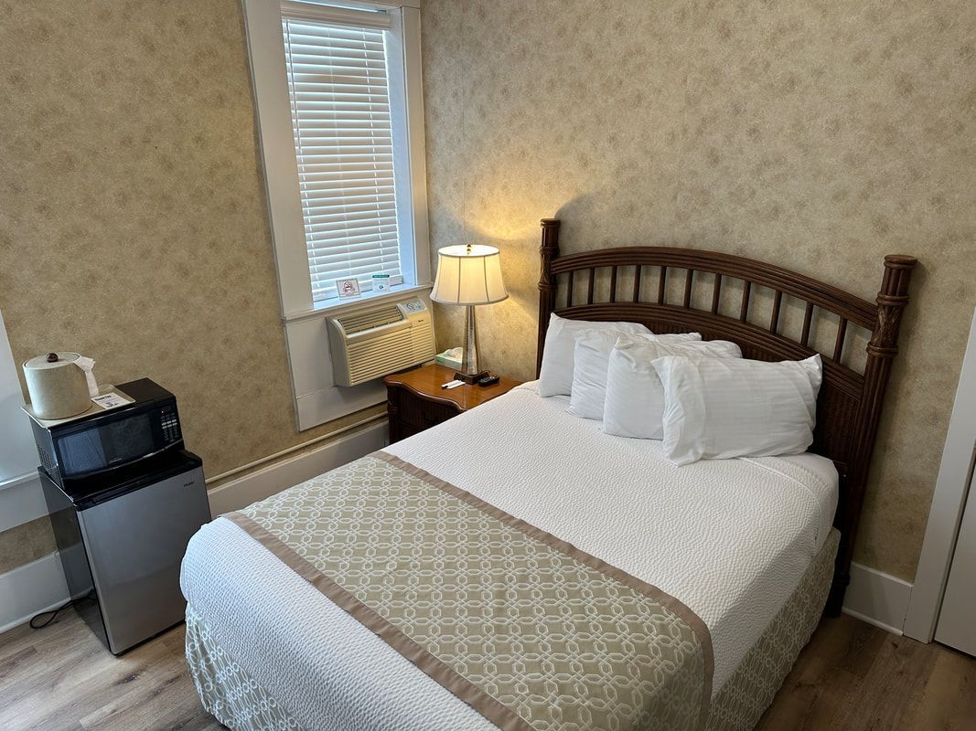 A hotel room with a bed , microwave , and refrigerator.
