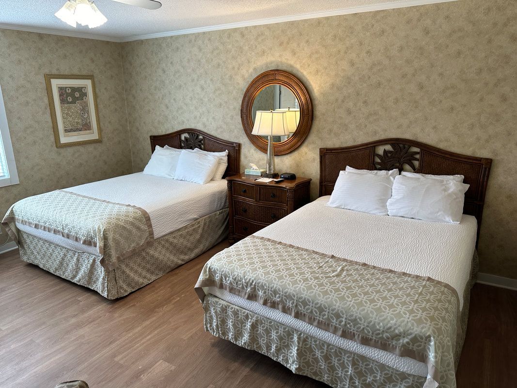 A hotel room with two beds and a mirror.