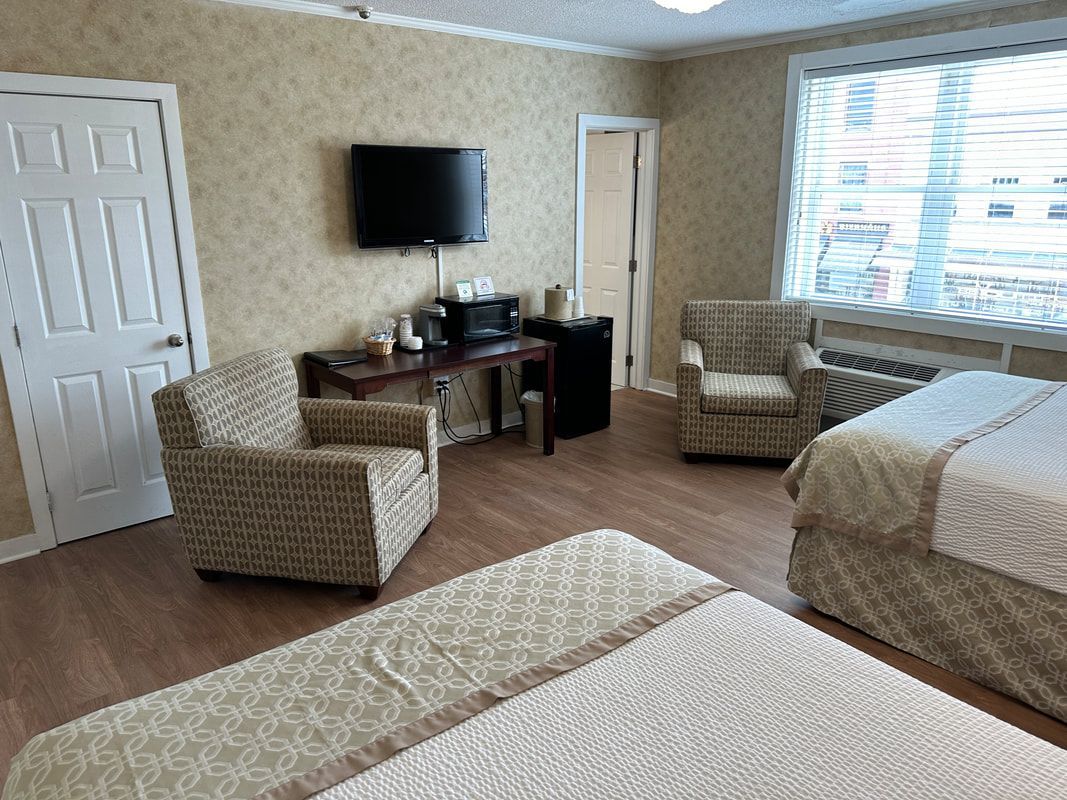 A hotel room with two beds , two chairs , a desk and a television.