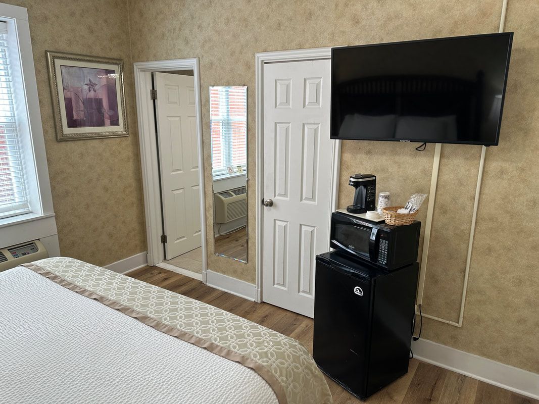 A hotel room with a bed , television , microwave and refrigerator.