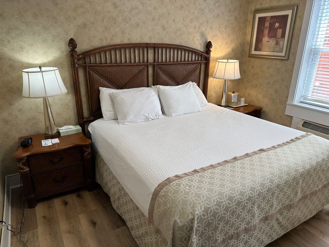 A bedroom with a bed , nightstand , lamps and a window.