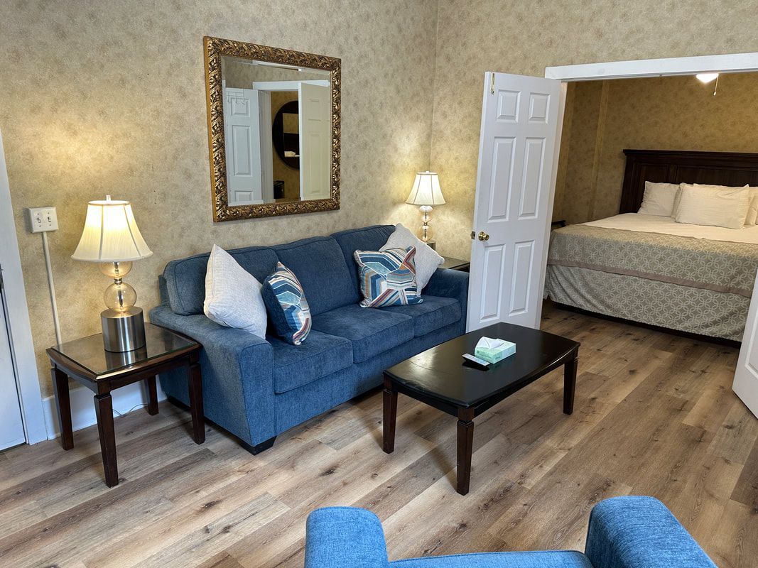 A living room with a couch , chair , coffee table and a bed.