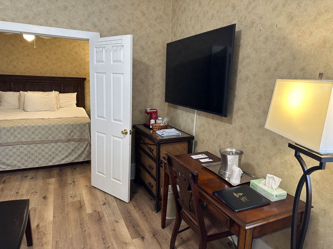 A hotel room with a bed , desk , lamp and television.