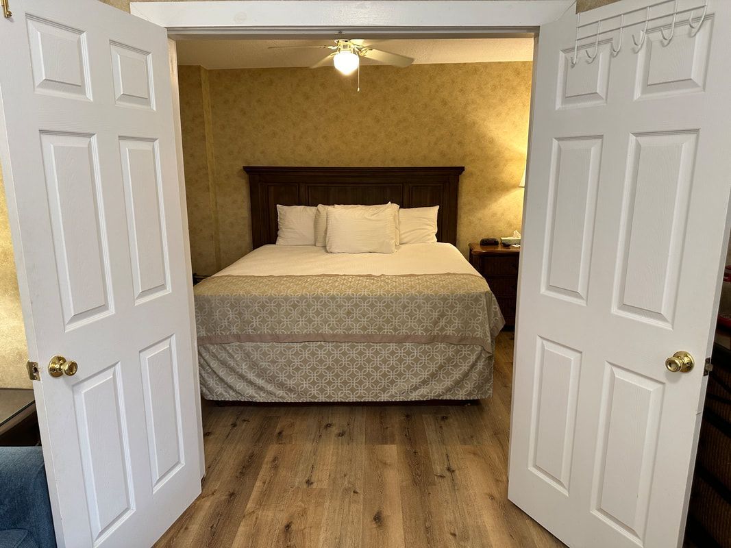 A bedroom with a bed and two doors open.