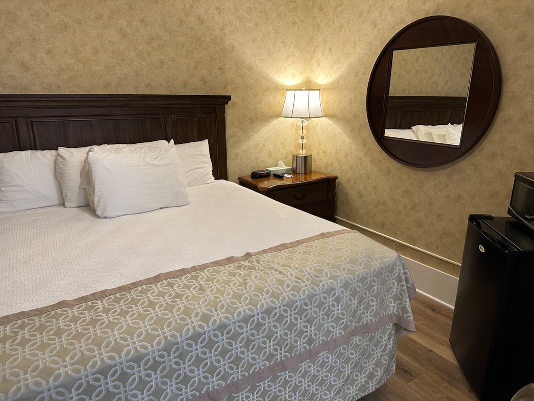 A hotel room with a king size bed and a round mirror