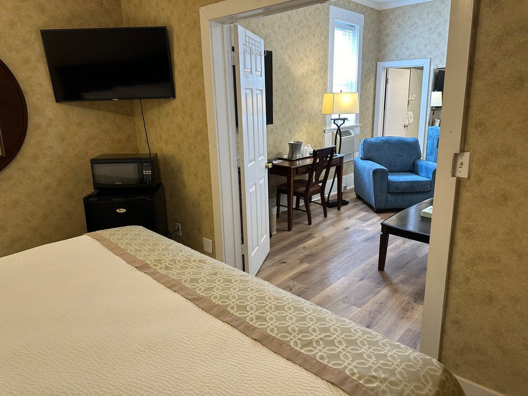 A hotel room with a bed , television , desk , chair and coffee table.