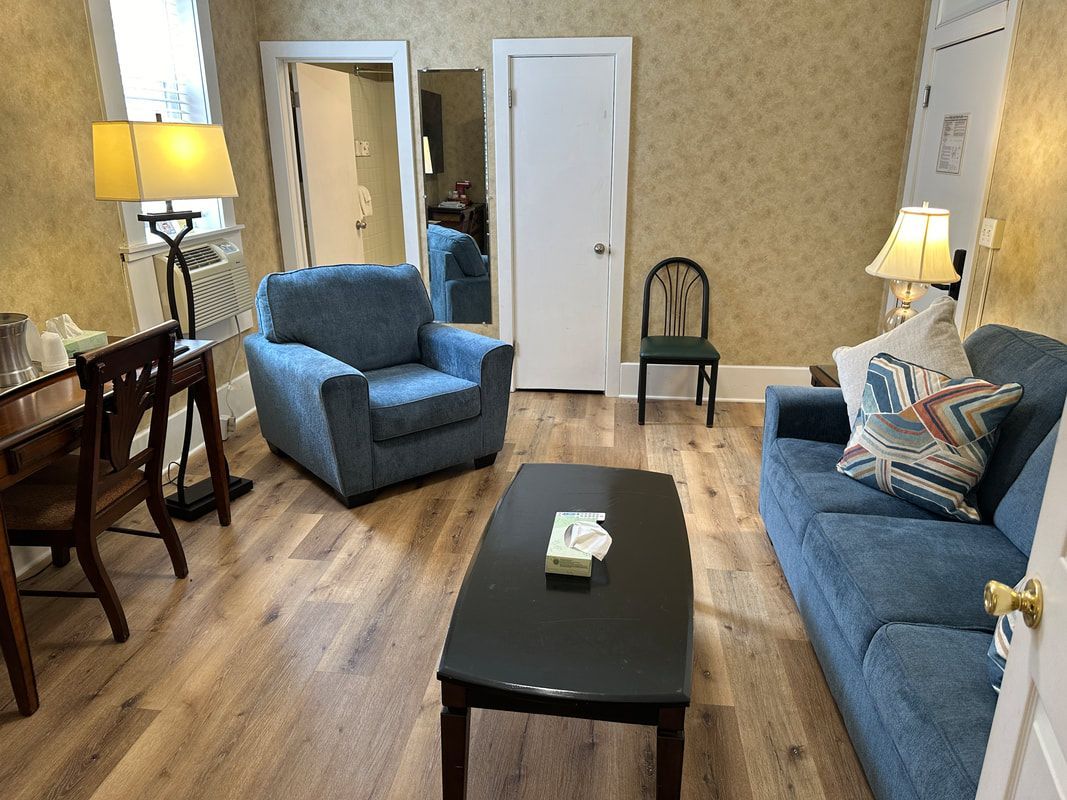 A living room with a couch , chair , coffee table and desk.