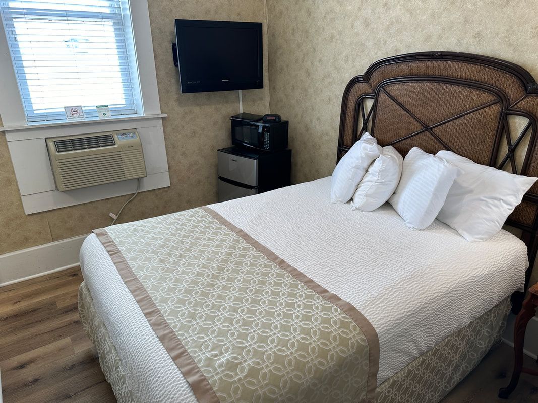 A hotel room with a bed , television and air conditioner.