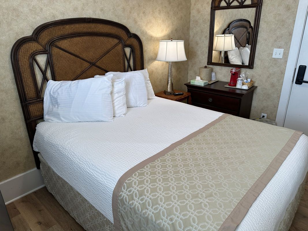 A hotel room with a bed , nightstand , mirror and lamp.