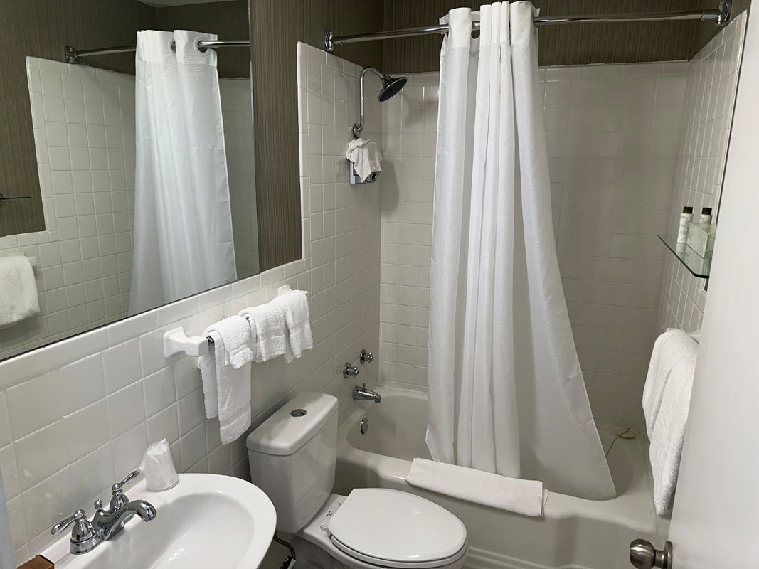 A bathroom with a toilet , sink , bathtub and mirror.