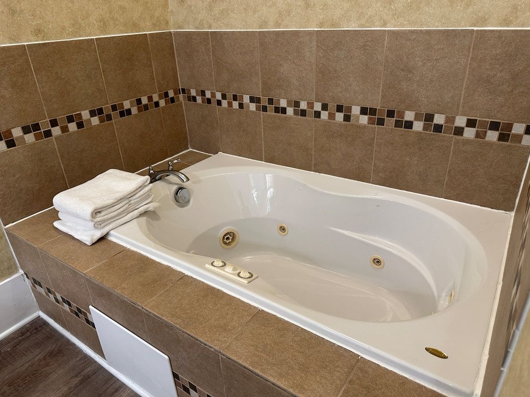 A bathroom with a jacuzzi tub and a stack of towels.