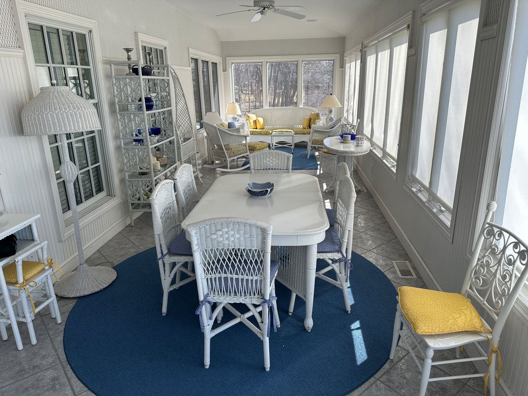 A sun room with a table and chairs and a blue rug.