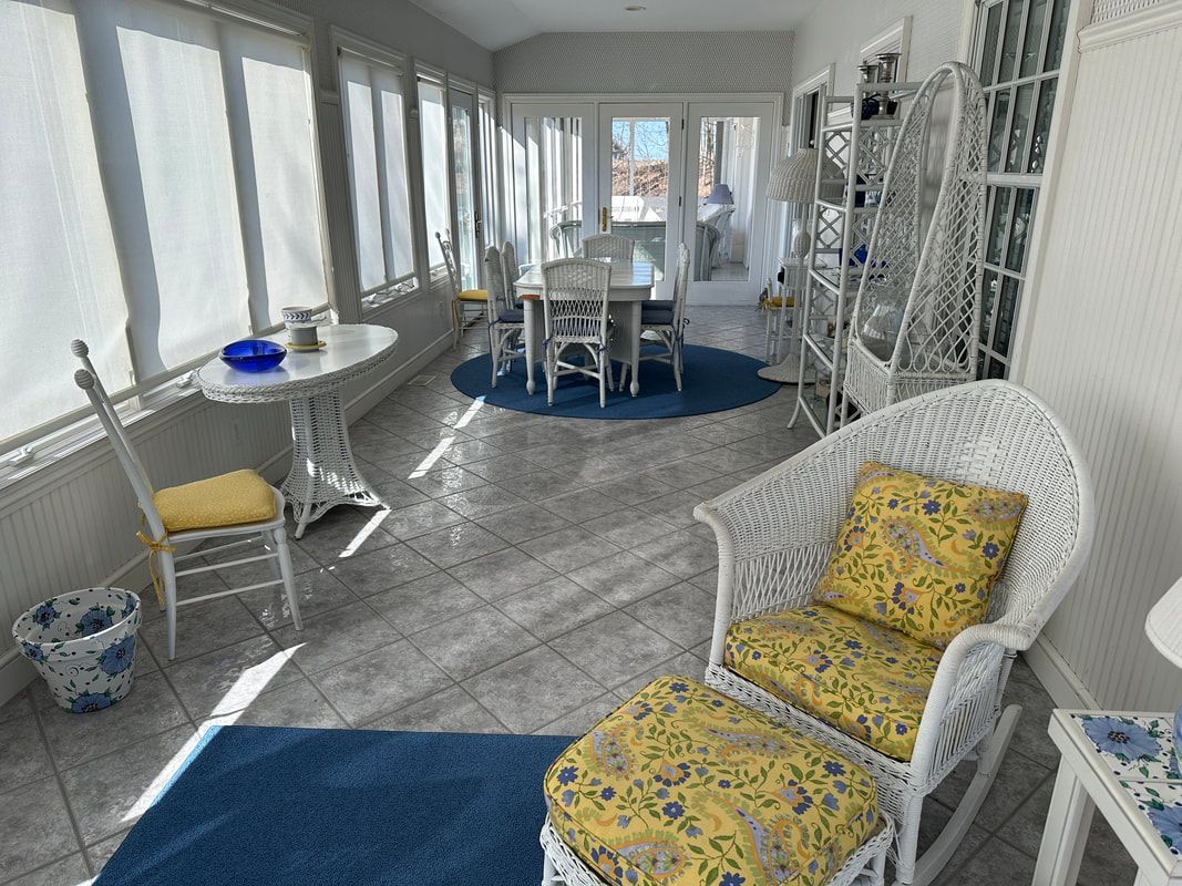 A living room with a wicker chair , table and chairs.