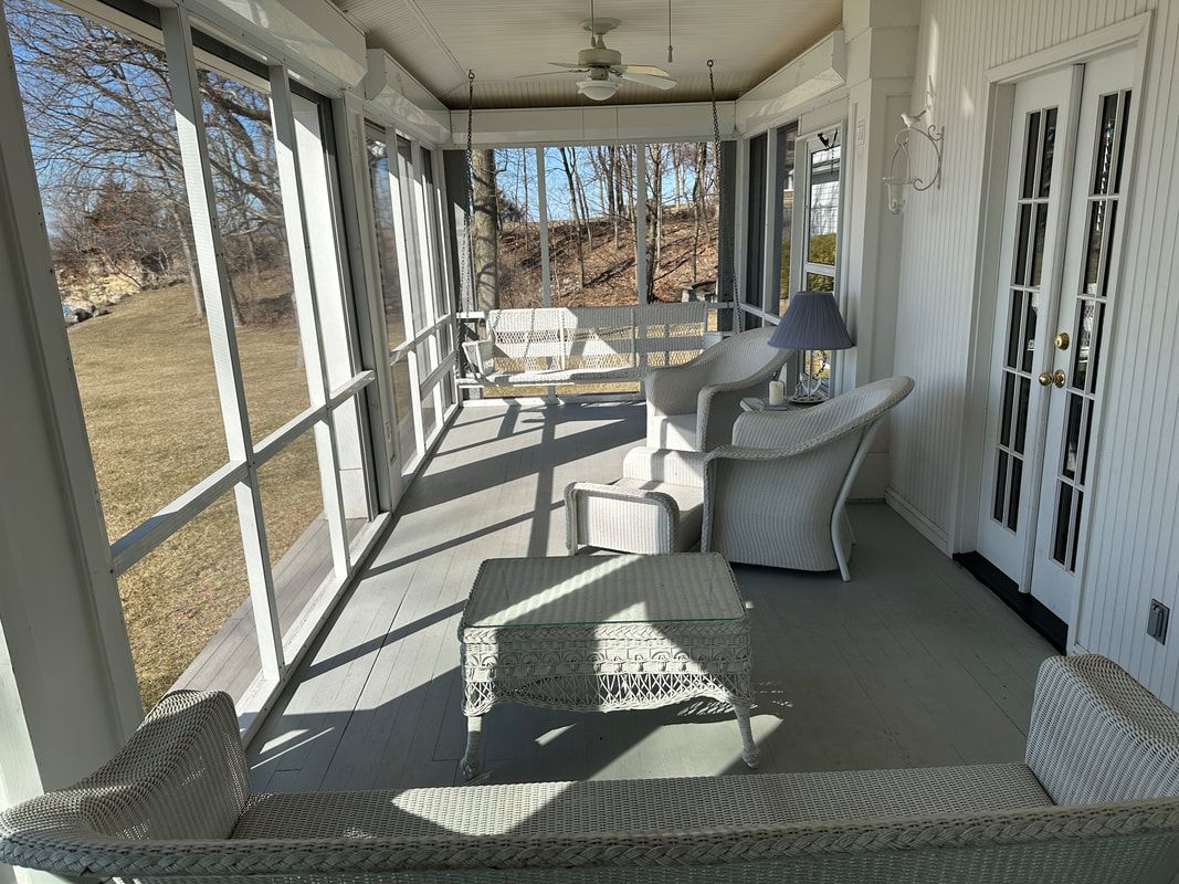 A screened in porch with wicker furniture and a couch.