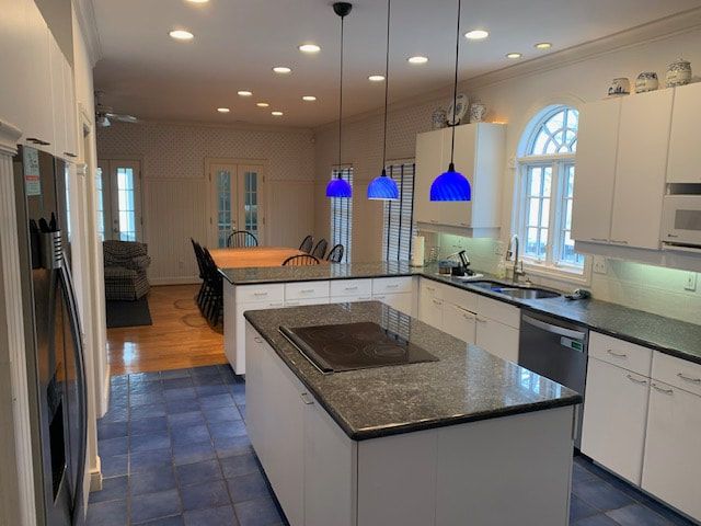 A kitchen with white cabinets and black counter tops