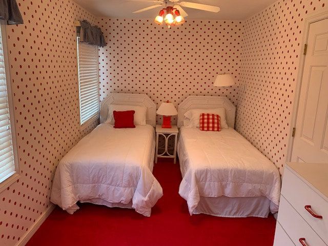 A bedroom with two twin beds and red polka dot wallpaper