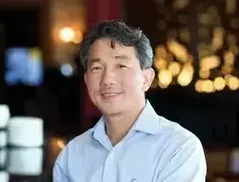 A man in a blue shirt is smiling for the camera in a restaurant.