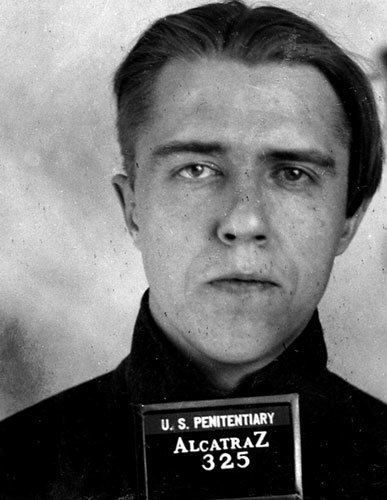 A black and white photo of a man with a name tag on his chest.