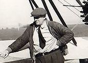 A man in a hat and tie is standing on a boat.
