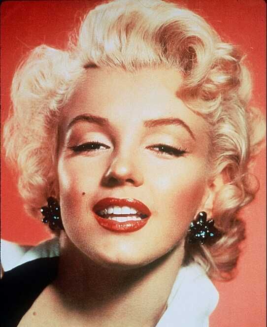 A close up of a woman 's face with blonde hair and red lipstick.