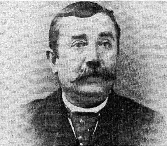A black and white photo of a man with a mustache.