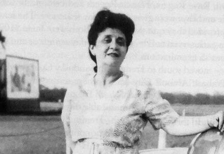 A woman is standing in front of a truck in a black and white photo.
