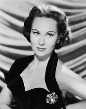 A black and white photo of a woman in a black dress and brooch.
