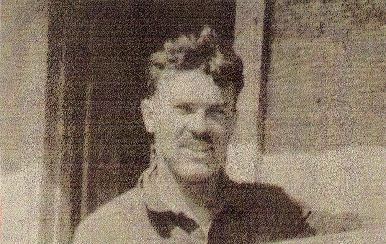 A black and white photo of a man with glasses and a mustache.